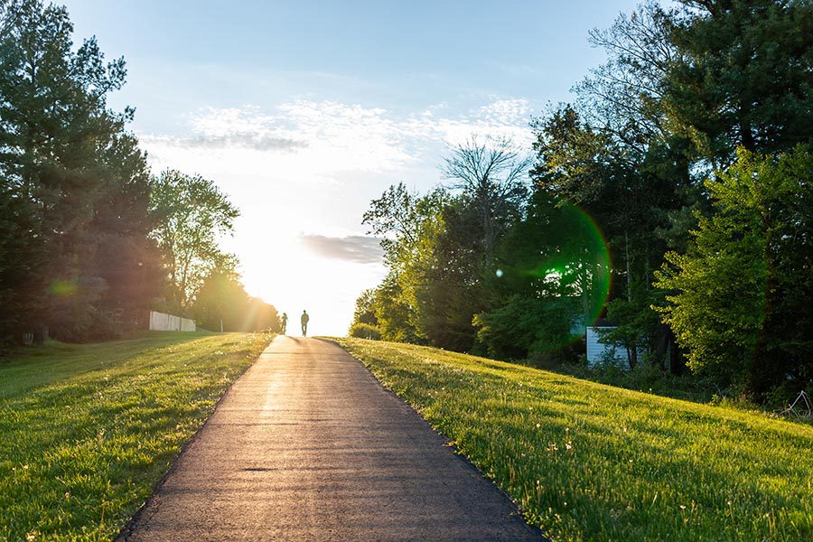 Dresher, PA Insurance - An Asphalt Walking Path Stretches Into the Distance, Sun Shining Low on a Summer Day
